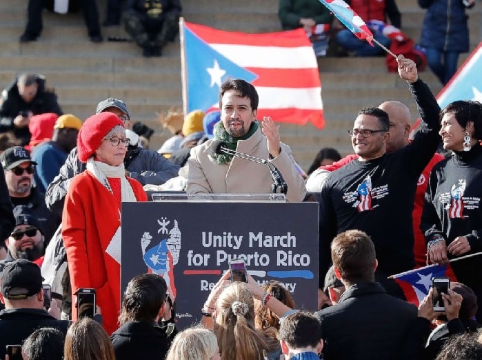 Lin-Manuel Miranda speaking in front of many people while raising fund for Hurricane Maria